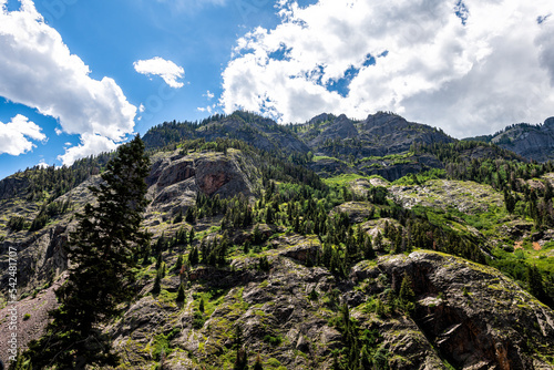 Looking up low angle view of rock canyon wall cliff near Ouray Colorado Million Dollar Highway with San Juan rocky mountains in summer, blue sky clouds photo
