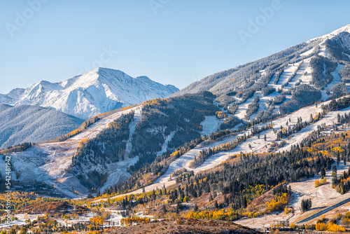Aspen, Colorado buttermilk ski resort town slopes hill in Rocky mountains view on sunny day with winter snow on yellow foliage autumn trees