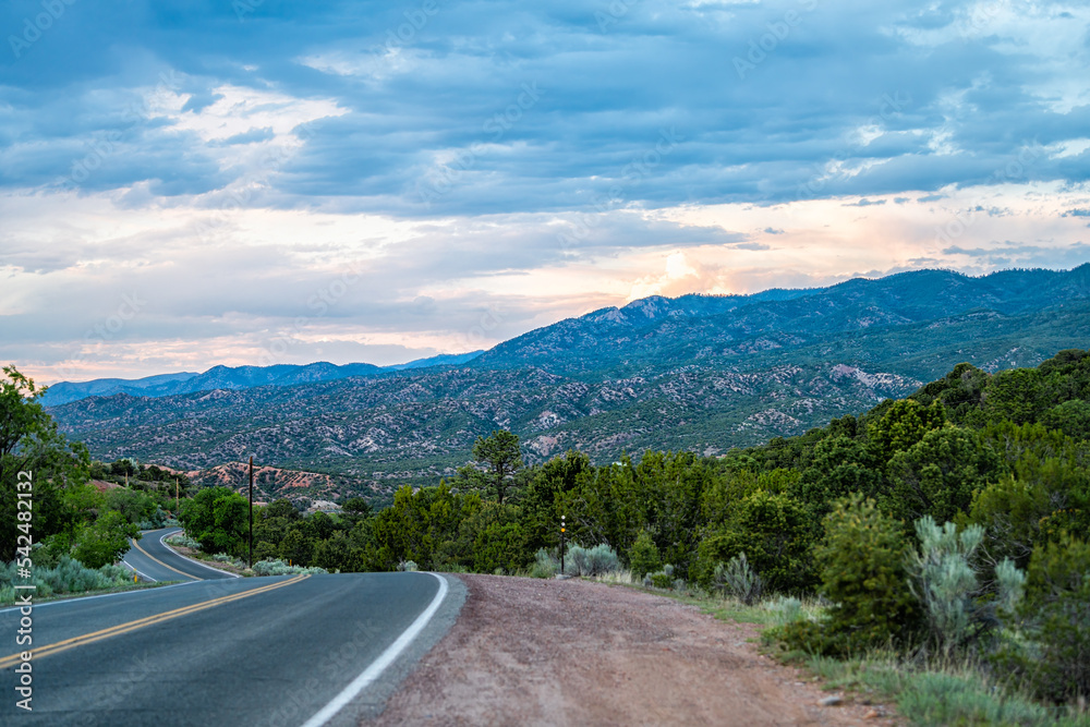 Fototapeta premium Sangre De Cristo mountains sunset on Bishops Lodge Road street in Santa Fe, New Mexico with pink sunlight by Tesuque residential community
