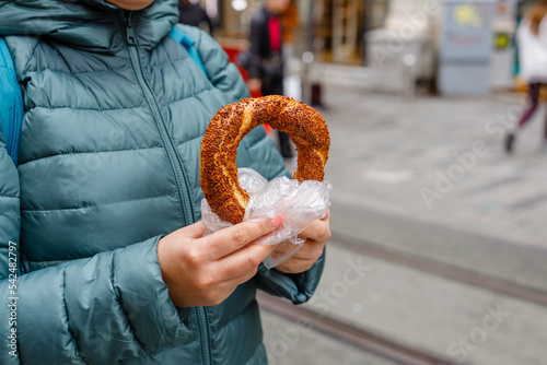 Turkish bread simit in hand. Traditional baked bagel in Turkey sold as street food and eaten with tea for breakfast or lunch