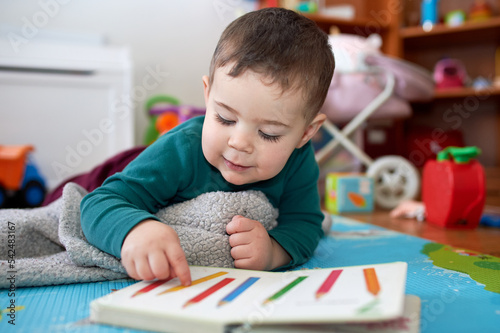 young boy playing and looking at books in his room