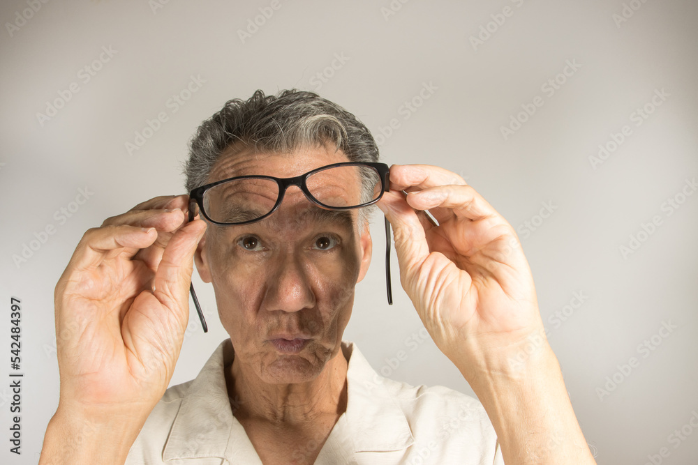 Mature man cleaning and checking his eye glasses to see if there clean Mature man cleaning and checking his eye glasses to see if there clean