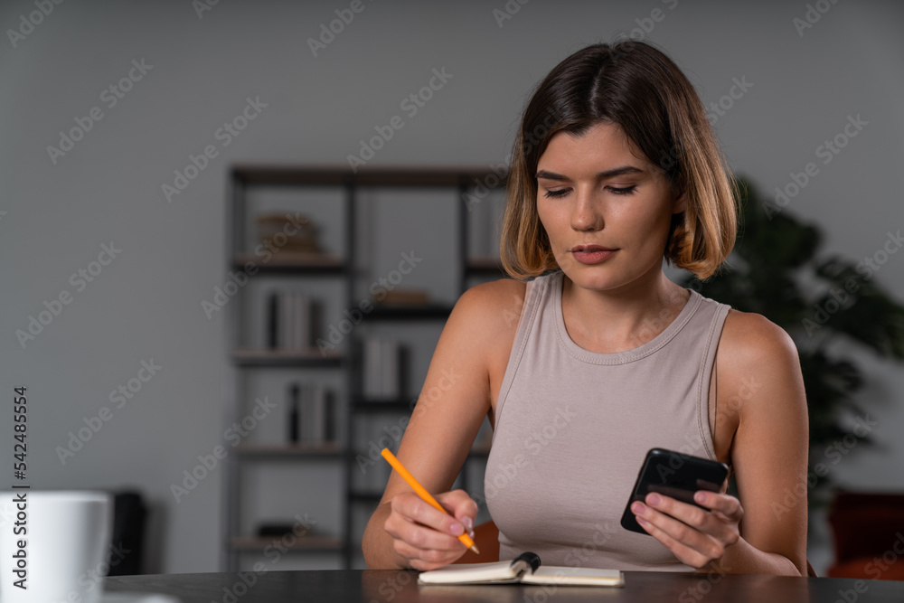 Thoughtful businesswoman in casual wear holding smartphone typing taking notes Thoughtful businesswoman in casual wear holding smartphone typing taking notes