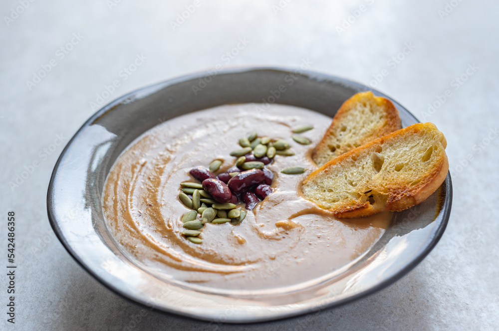 Healthy vegan pumpkin soup with red beans, pumpkin seeds, coconut cream and slices of fried bread Healthy vegan pumpkin soup with red beans, pumpkin seeds, coconut cream and slices of fried bread