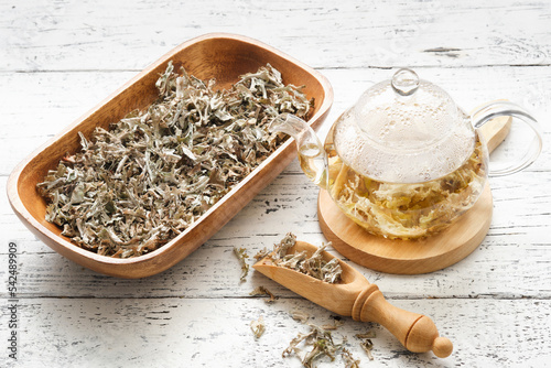 Glass teapot of herbal Icelandic moss tea. Wooden scoop and bowl of dried Iceland moss. Cetraria islandica - latin name of plant. Alternative herbal medicine. photo