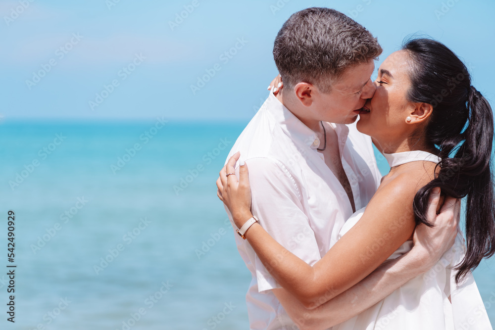 Young couple in love outdoor. Happy man Kissing to his woman at tropical beach. Girlfriend with boyfriend resting travel at sunrise in summer. Young couple in love outdoor. Happy man Kissing to his woman at tropical beach. Girlfriend with boyfriend resting travel at sunrise in summer.
