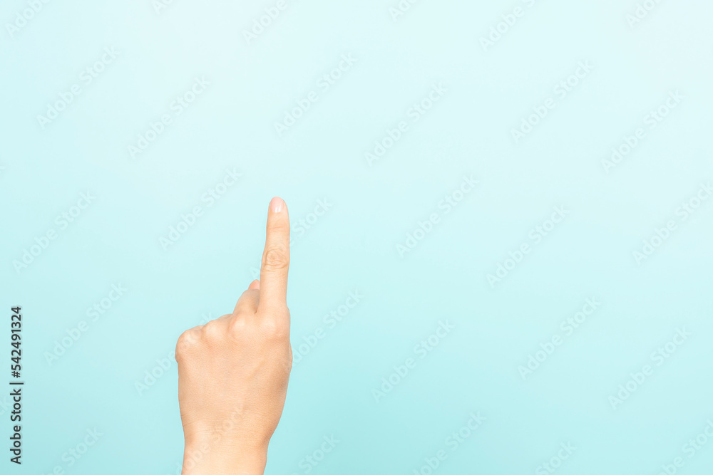 Hand gesture show, touch, index, press, select something. Woman pointing up with index finger on light blue background. Female hand shows number one. Front view