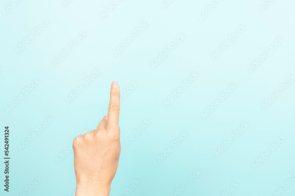 Hand gesture show, touch, index, press, select something. Woman pointing up with index finger on light blue background. Female hand shows number one. Front view Hand gesture show, touch, index, press, select something. Woman pointing up with index finger on light blue background. Female hand shows number one. Front view