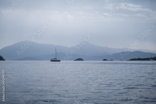sea and mountains silhouette view in cloudy mist day, Blue Sea and shade of mountain, empty peaceful nordic landscape with sailing boats 