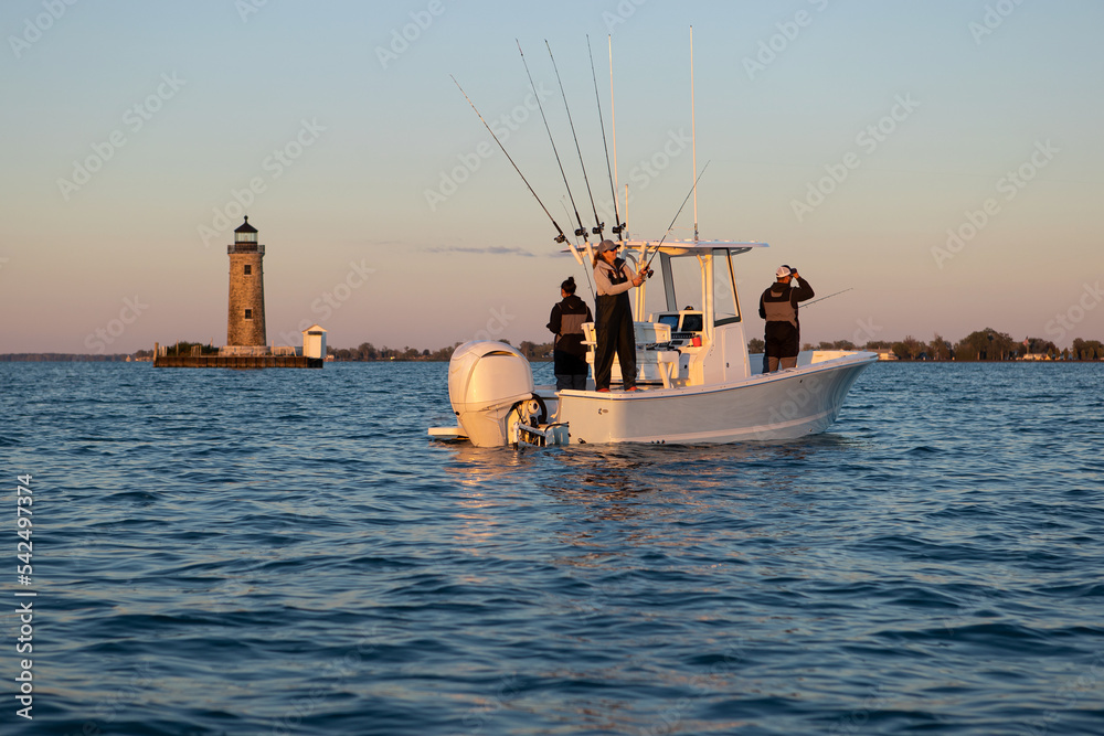 People fishing on a boat with a lighthouse in the background. Stock Photo