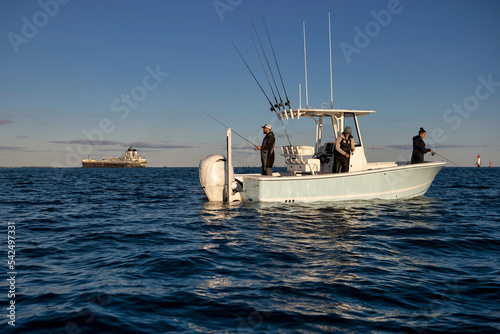 People fishing on a boat with a freighter in the background.