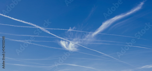 airplane trails of condensed air crisscrossing each other against the blue sky