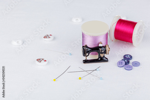 still life of a skein of thread for sewing, needles, buttons, sewing machine on a white background