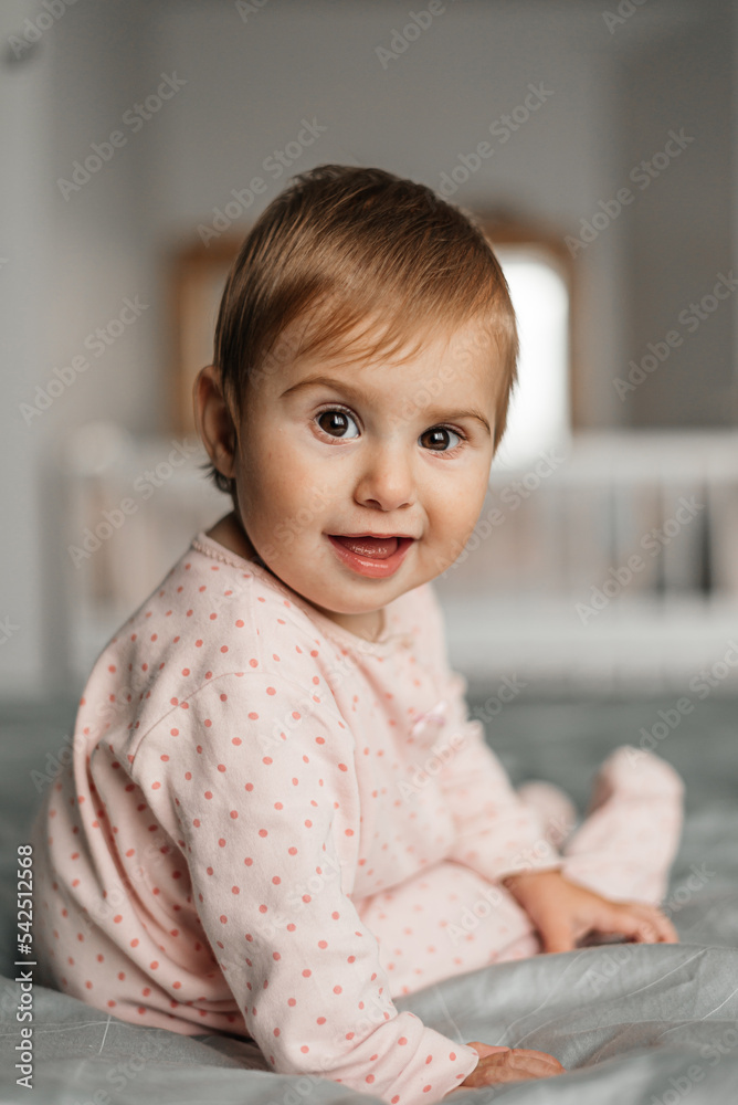 Portrait of a crawling baby on a bed in her room