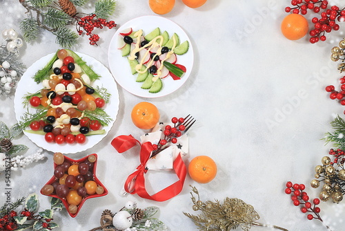 Christmas New Year dishes, for a traditional holiday salad with cheese, olives, tomatoes and grapes, fir branches and decorations, food design idea, selective focus