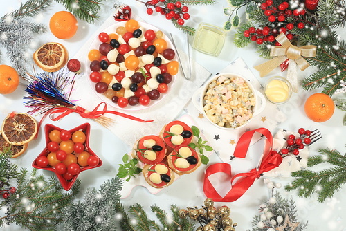 Christmas New Year dishes, for a traditional holiday salad with cheese, tomatoes, olives and grapes and caprese bruschetta, olivier salad, spruce branches and decorations, food design idea photo