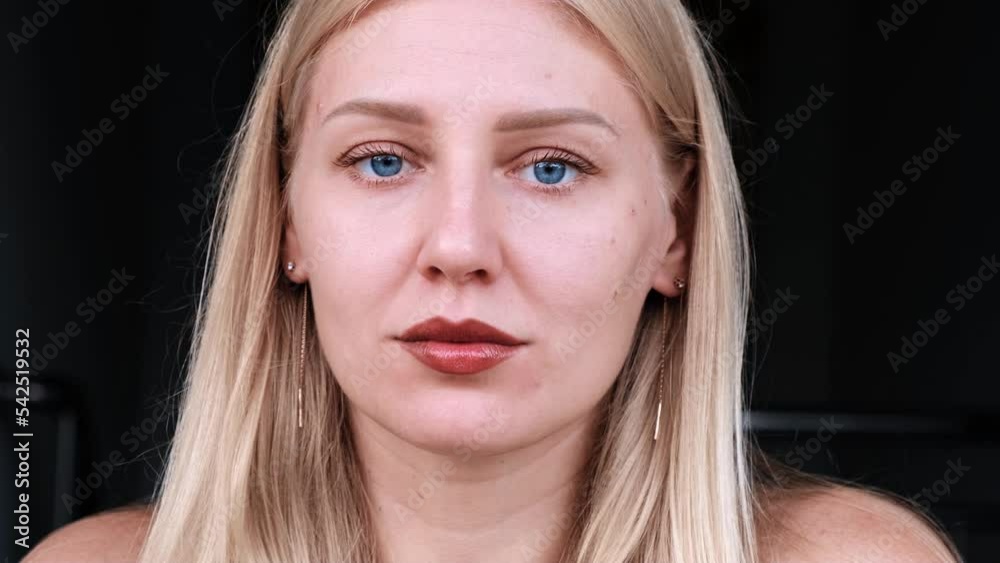 Natural beauty and self-care. Young attractive blonde woman with blue eyes looks at her face in the mirror looking for wrinkles. Aging and preservation of youth. Health and youth of skin.