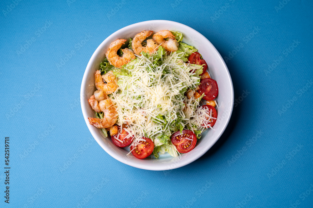 salad with shrimp and parmesan cheese in a plate on a blue background salad with shrimp and parmesan cheese in a plate on a blue background