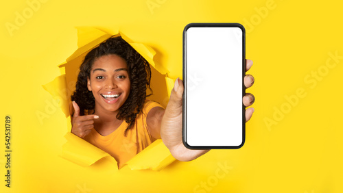 Happy Black Lady Showing Cellphone Screen In Torn Yellow Paper © Prostock-studio