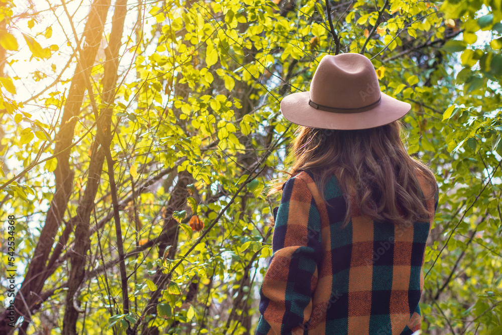 Rear View Of A Young Woman Walking Through A Park On A Sunny Autumn Day, Wearing A Vintage Hat And Jacket. Autumn Image.