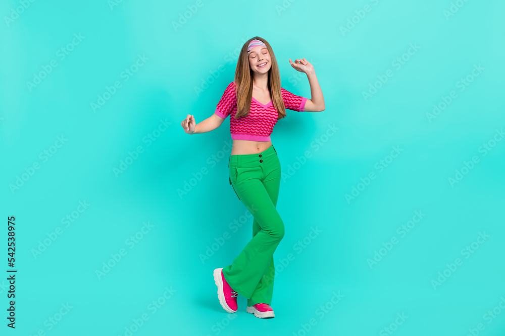 Full length photo of charming dreamy school girl dressed pink crop top flare trousers dancing having fun isolated teal color background Full length photo of charming dreamy school girl dressed pink crop top flare trousers dancing having fun isolated teal color background