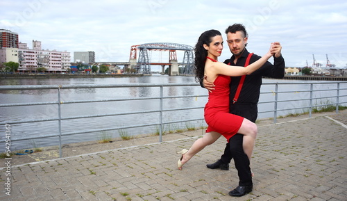 Young, beautiful and professional couple dancing tango on the quay of the river