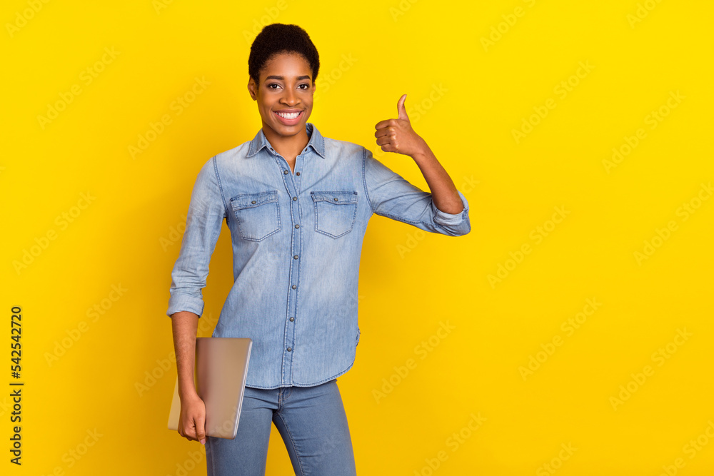 Photo of cheerful person hold netbook hand finger show thumb up feedback rate isolated on yellow color background Photo of cheerful person hold netbook hand finger show thumb up feedback rate isolated on yellow color background