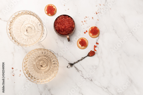 Elegant glass of champagne with red caviar on golden spoon and metal container of caviar, Gourmet food close up, appetizer, selective focus, place for text