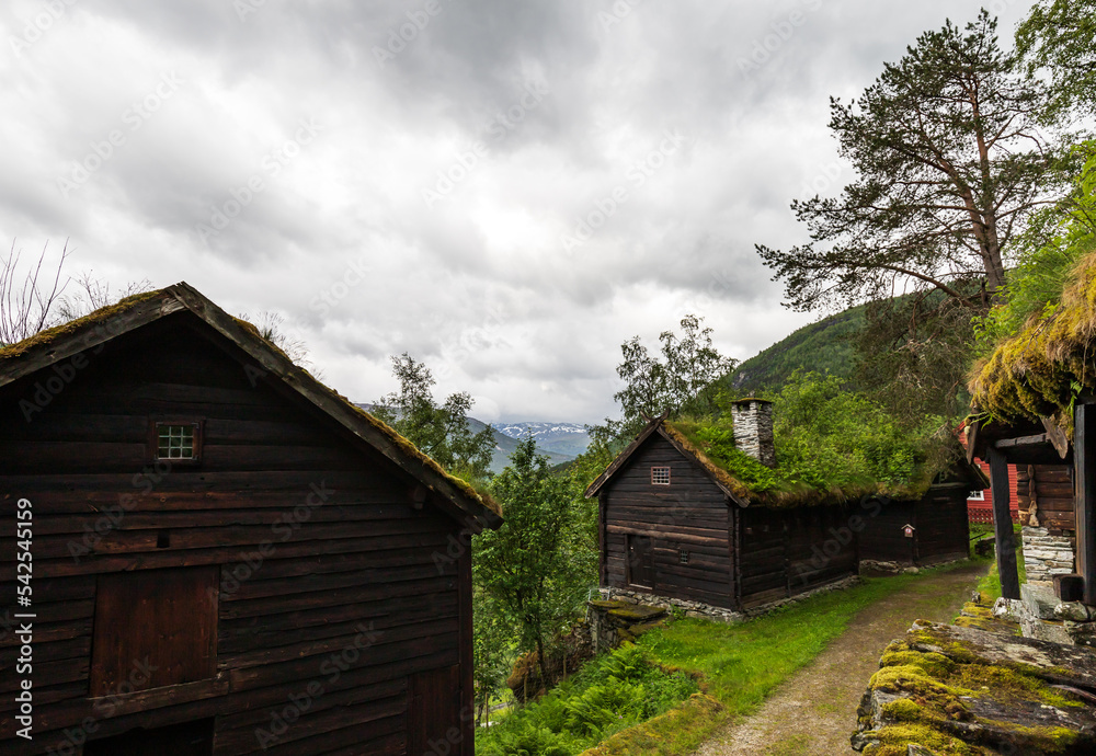 Farm Houses Architecture, Snow Capped Mountain Background At Stalheim Open Air Folk Museum With Tonneberg Collection Exhibiting Middle Age Rural Norway In Vossestrand. Farm Houses Architecture, Snow Capped Mountain Background At Stalheim Open Air Folk Museum With Tonneberg Collection Exhibiting Middle Age Rural Norway In Vossestrand.