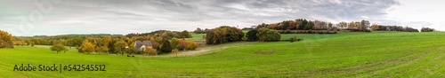 Panoramic rural autumn landscape in North Rhine Westphalia in Germany. Farm house in the middle of a huge green field.