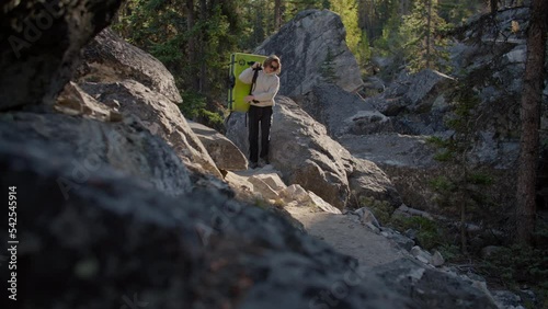 Rock climber puts crash pad on back in boulder field