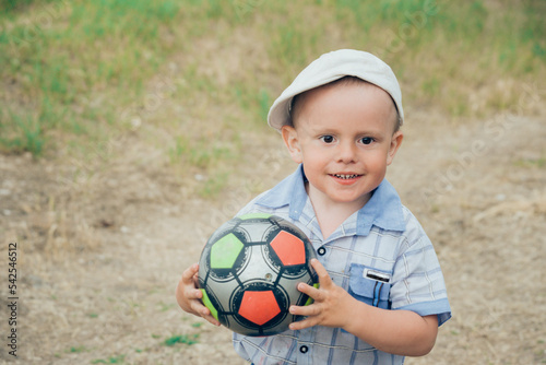 boy holding his football outdoors on a sunny summer day
