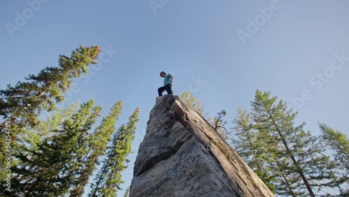 Man walks to the edge of giant boulder in forest, rock climbing, bouldering