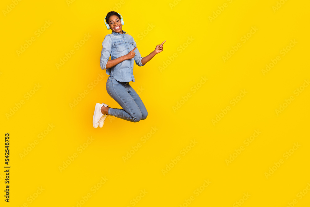 Full length photo of active person wireless earphones direct fingers empty space isolated on yellow color background