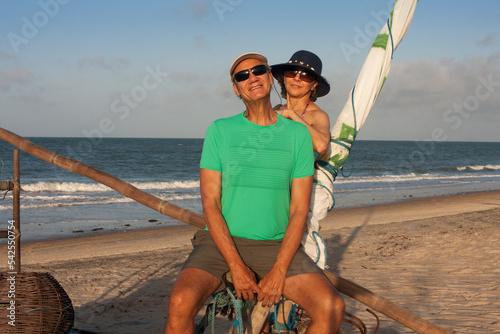 Mature couple at the beach in Combuco, Brazil, sitting on a Jangada a fishing boat typical in Brazil photo