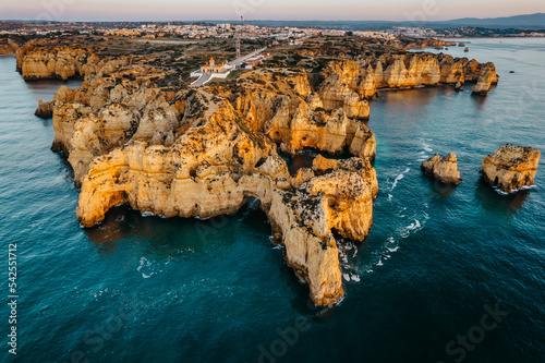 Obraz na płótnie Coastal golden cliffs at sunrise in Ponta da Piedade near Lagos,Portugal.Spectacular rock formations with caves,and sea arches,lighthouse.Summer vacation by Atlantic Ocean.Famous beach in Algarve w salonie