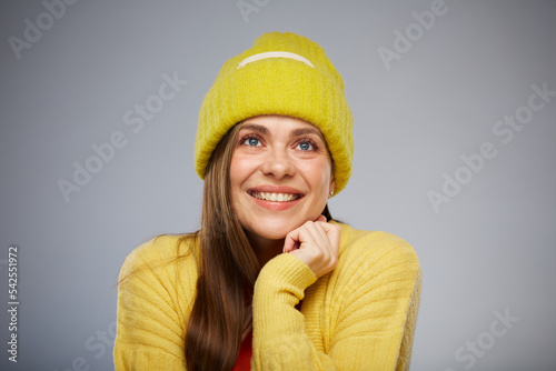 Happy smiling woman looking up wearing winter yellow hat. Advertising female studio portrait.