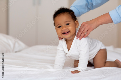 Adorable Black Baby Getting Massage From Loving Mom While Relaxing On Bed