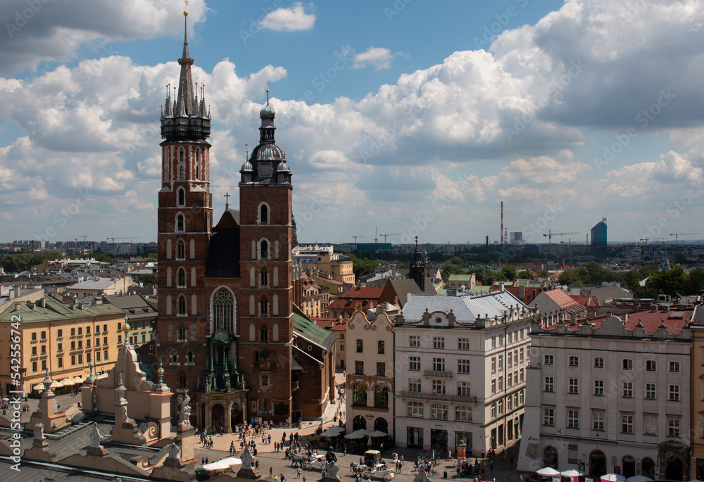 Naklejka premium Krakow, Poland, July the 15th 2022. The crowded central market square of Krakow with St Mary's Basilica by the side of it.