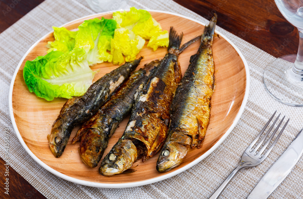 Grilled on fire sardines served with fresh greens, popular Mediterranean food