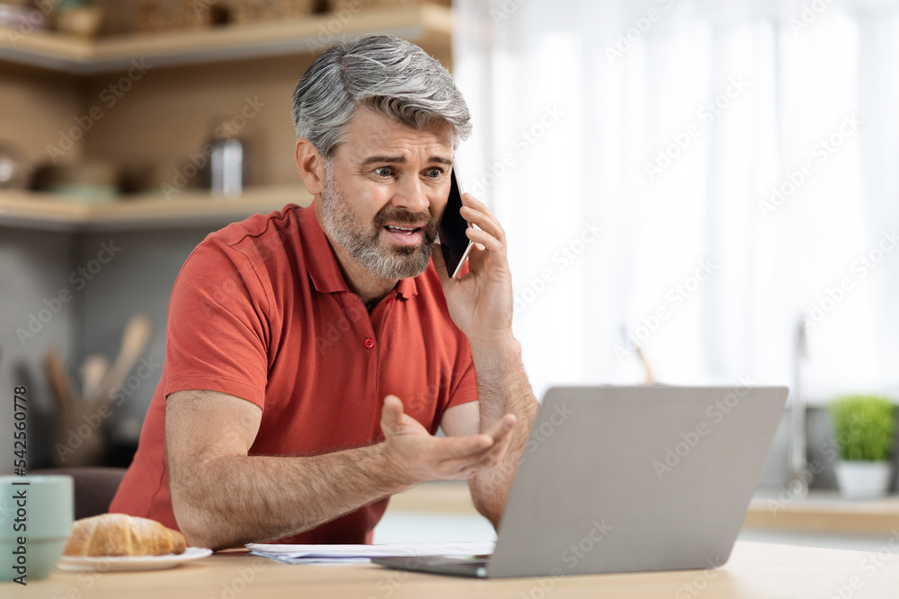 Angry middle aged entrepreneur working from home, having phone call Angry middle aged entrepreneur working from home, having phone call