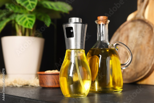 Bottles with cooking oil and bowl of sunflower seeds on black table in kitchen