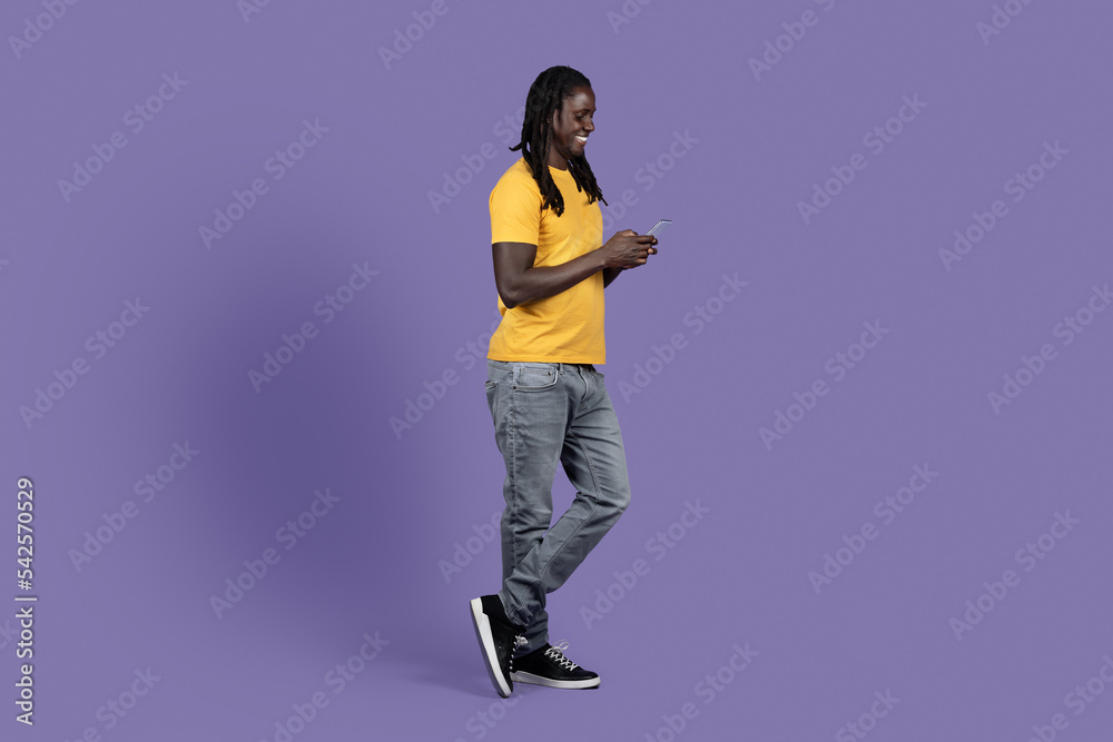 Side view of cheerful african american guy using cell phone Side view of cheerful african american guy using cell phone