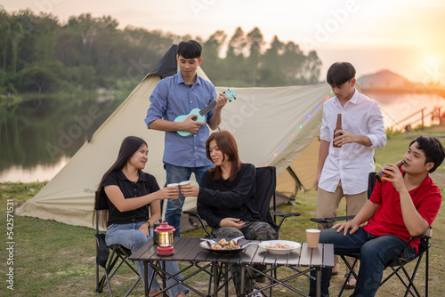 Young people are happy to camp on a lake with forests and mountains in the background. © Pornprasit Panada