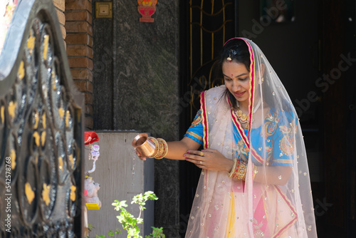 Indian Hindu married woman, bahu pouring water to tulsi basil plant. Ritual, belief, worship, offering, pray, culture, tradition, traditional clothes, pooja, lota, diya, tulsi vivah, suhaag, holy, jal