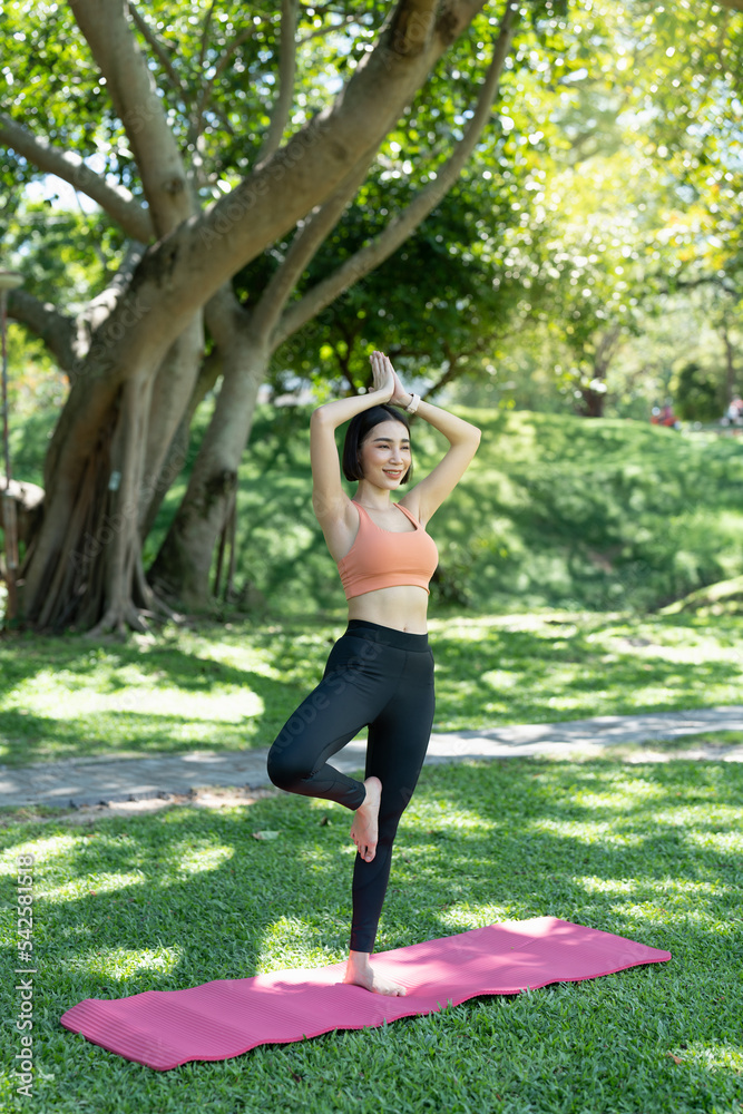 Young attractive girl is doing advanced yoga asana on the fitness mat in the middle of a park. Young attractive girl is doing advanced yoga asana on the fitness mat in the middle of a park.