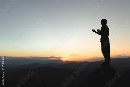 Man praying at sunset mountains, concept vacations outdoor harmony with nature landscape, Travel Lifestyle spiritual relaxation emotional meditating.