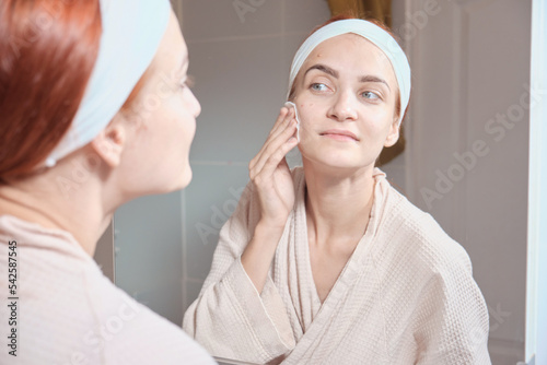 Beauty Routine. Smiling female cleansing skin with cotton pads. Woman removing makeup, skin care treatments at home. The second stage of cleansing, applying a tonic to equalize the ph of the skin