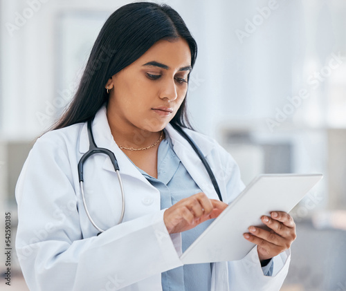 Health, healthcare and doctor on tablet in hospital working on patient records, researching medicine and planning schedule. Medical professional, female and worker from India on tech browsing web.