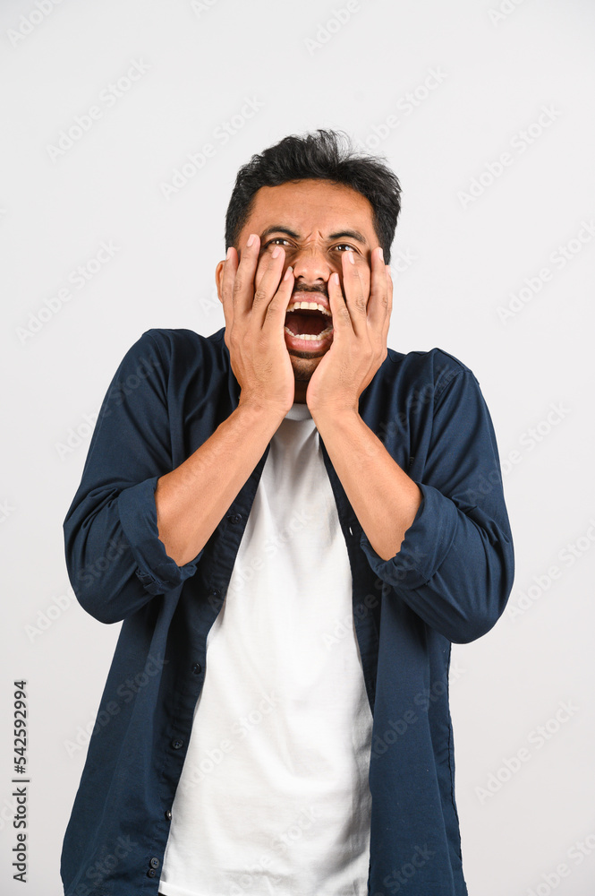 Portrait of Disappointed young asian man in blue shirt annoyed angry in furious gesture isolated on white background Portrait of Disappointed young asian man in blue shirt annoyed angry in furious gesture isolated on white background